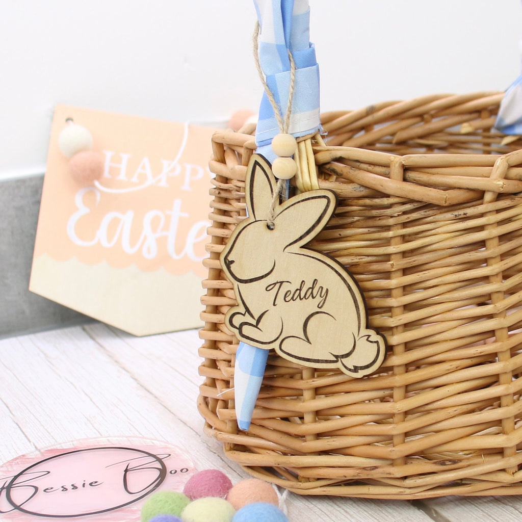 Easter basket wooden tag to be used as an Easter Decoration. The 8cm tag is in the shape of a bunny cut from 3mm Plywood. The item can include personalised text, such as the name of a child. In the image the tag is shown attached to a wicker basket.